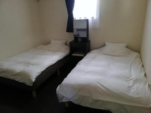 duas camas sentadas uma ao lado da outra num quarto em YUFUKANⅡ em Yufu