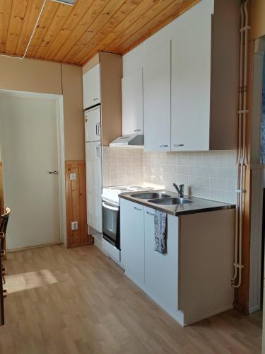 a kitchen with white cabinets and a sink at Maalaistalon päätyhuoneisto Merikarvialla in Tuorila