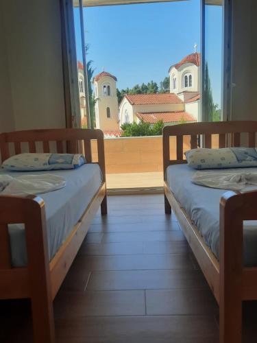 two beds in a room with a large window at Vila Lefteria in Këlcyrë