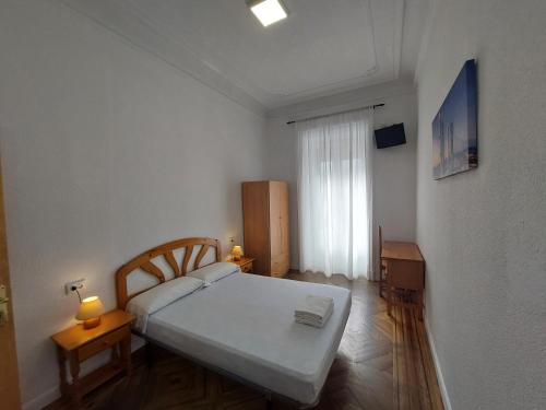 Habitación pequeña con cama y ventana en Hostal Miralva, en Madrid