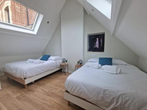 2 Betten in einem weißen Zimmer mit 2 Fenstern in der Unterkunft Maison T3 Mérignies in Mérignies