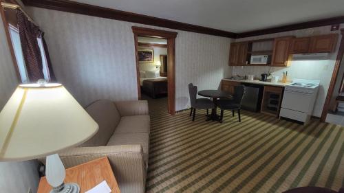 a living room with a couch and a kitchen at Ramada by Wyndham Saginaw Hotel & Suites in Saginaw