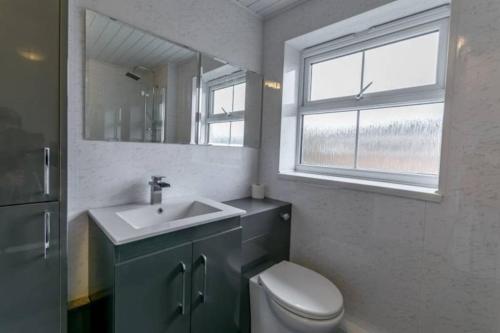 a bathroom with a sink and a toilet and a window at 5 Bedroom 5 Bath sleeps 10 close Luton Airport M1 in Caddington