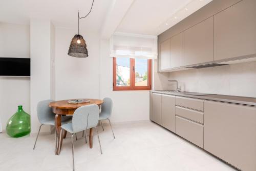 uma cozinha branca com uma mesa de madeira e cadeiras em Contrada del Nonno Apartments (city center - private parking on-site) em Rovinj
