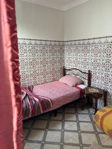 ein kleines Schlafzimmer mit einem Bett mit rosa Laken in der Unterkunft Une maison au centre de l'ancienne Médina in Marrakesch