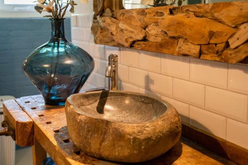 ein Kupferwaschbecken auf einem Tisch mit einer Vase in der Unterkunft Vakantiewoning Le Garaazje in 's-Gravendeel