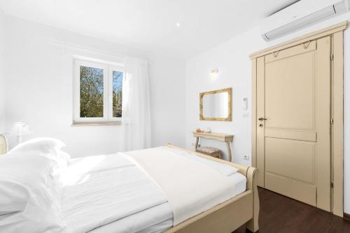 a white bedroom with a bed and a window at Kastelir in Kaštelir