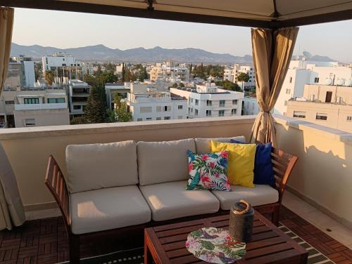 a couch on a balcony with a view of the city at Rainbow 7th floor penthouse apartment in Engomi