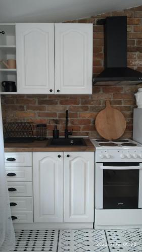 a kitchen with white cabinets and a brick wall at Apartman Stara Trešnja in Kladovo