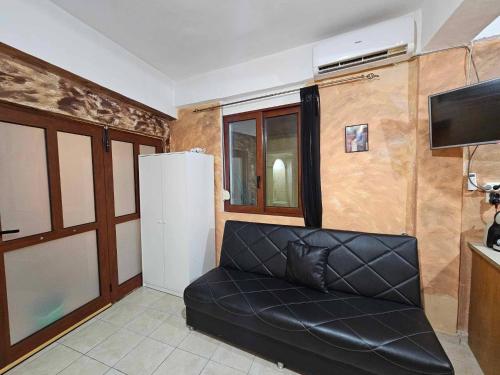a black leather couch in a living room with a tv at George's Guest House in Chania Town