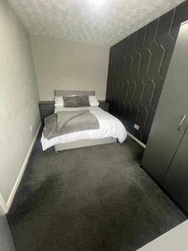um pequeno quarto com uma cama e uma parede em Cosy, modern Apartment em Darlaston