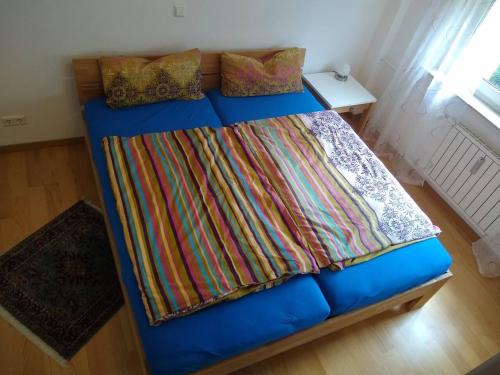 a blue bed with a colorful blanket on it at City Apartment WOB-Rothenfelde in Wolfsburg