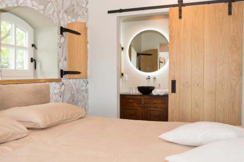 1 dormitorio con cama con espejo y lavamanos en B&B De NieuwenHof 'De Voorkamer' en Melderslo