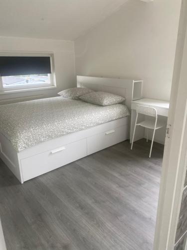 a white bedroom with a bed and a desk at De Keizersmantel in Son