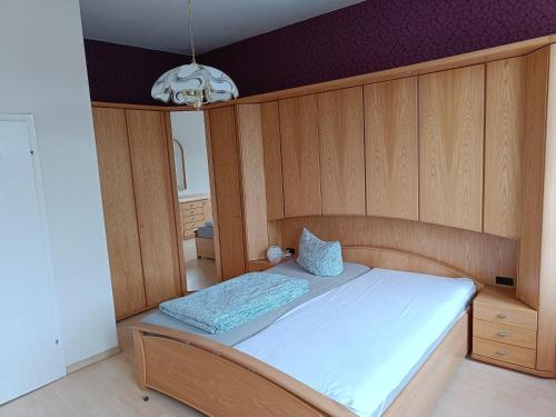 a bedroom with a bed with wooden walls and a chandelier at FeWo Wüste Worth in Stendal