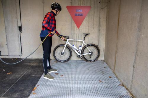 a man is holding a bike with a hose at Café Coureur Houffalize in Houffalize