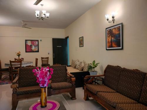 a living room with chairs and a vase of flowers on a table at Portofino TreeHouse in Lavasa