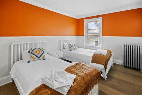 een slaapkamer met 2 bedden en een oranje muur bij Modern and Tropical Vibe 3BR Apt near AC Beach in Atlantic City