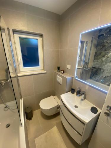 La salle de bains est pourvue de toilettes blanches et d'un lavabo. dans l'établissement Holiday home Maslina, à Orebić