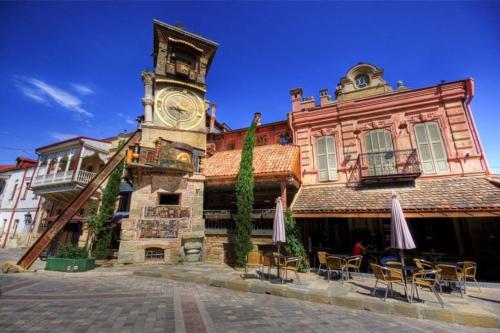 a building with a clock tower with chairs in front of it at Cozy House in Old Tbilisi in Tbilisi City