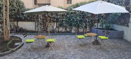 2 mesas y sillas con sombrillas en un patio en Casa Ribera Hotel Providencia, en Santiago