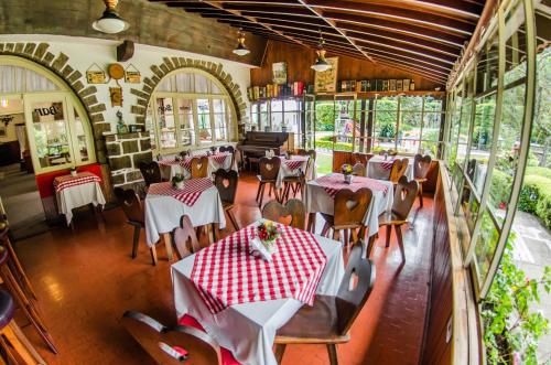 a restaurant with tables and chairs and a piano at Hotel Bucsky in Nova Friburgo