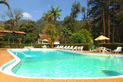 uma piscina com cadeiras e guarda-sóis num resort em Hotel Bucsky em Nova Friburgo