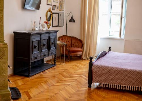 um quarto com uma cama, uma cómoda e uma cadeira em Maxim's place em Timisoara