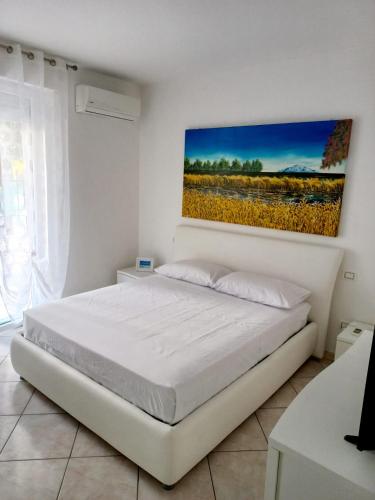 una camera bianca con un letto e un dipinto sul muro di BELLAVISTA House a San Salvo