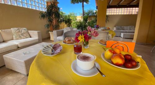 Hotel Il Girasole في فيلاسيميوس: طاولة صفراء مع صحن من الفاكهة وكوب من القهوة