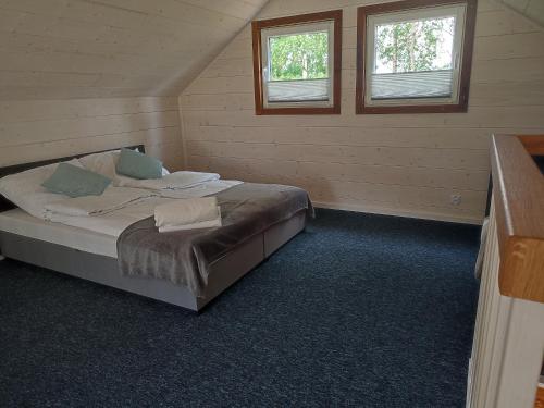 1 dormitorio con 1 cama en una habitación con 2 ventanas en Domek nad stawem z banią, en Brodnica