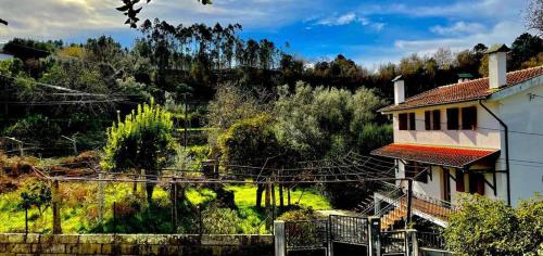 a house on a hill with trees and bushes at Casa da Pedrada in Ponte da Barca