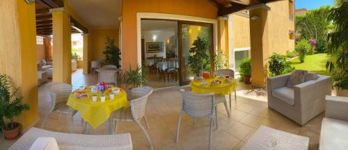 eine Terrasse mit 2 Tischen und einem gelben Tischtuch in der Unterkunft Hotel Il Girasole in Villasimius