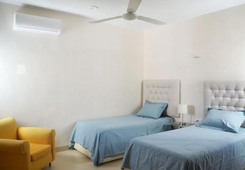 a bedroom with two beds and a yellow chair at An amazing stay in Progreso, close to everything in Progreso