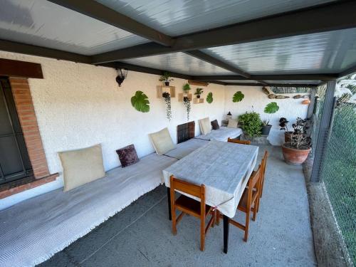 patio con tavolo e sedie sotto un tetto di Molí gran a Santa Eulalia de Ronsaná