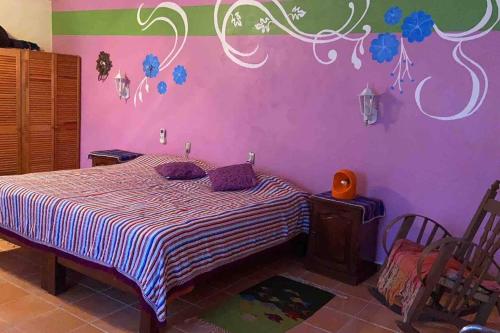 ein Schlafzimmer mit einem Bett und einer lila Wand in der Unterkunft Casa Blanca Zipolite, Dream House in Zipolite