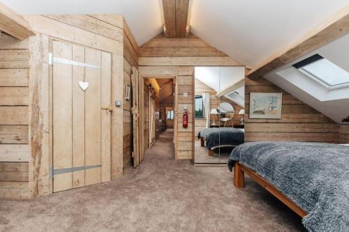 a bedroom with wooden walls and two beds at Owl Barn in Oxford