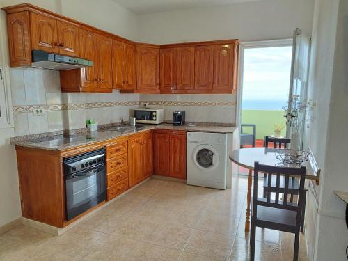 een keuken met houten kasten, een tafel en een wastafel bij Casa Olini in Breña Alta