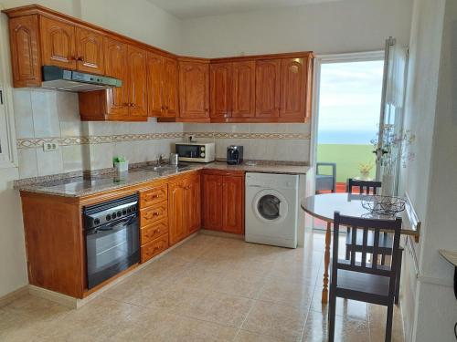 a kitchen with wooden cabinets and a table and a sink at Casa Olini in Breña Alta