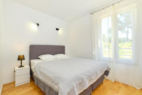 ein weißes Schlafzimmer mit einem Bett und einem Fenster in der Unterkunft Apartment Nora in Mali Lošinj