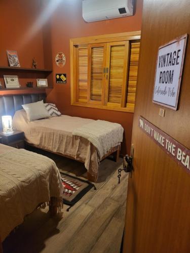 una habitación con 2 camas y un cartel en la puerta en Chalé Colorado Vibe, en Camanducaia