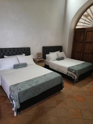 two beds sitting in a room with at Hotel Boutique Casa Gerar in Mompos