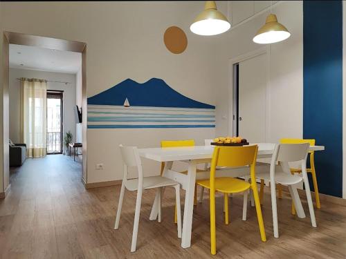 ein Esszimmer mit einem weißen Tisch und gelben Stühlen in der Unterkunft Toledo apARTment in Neapel