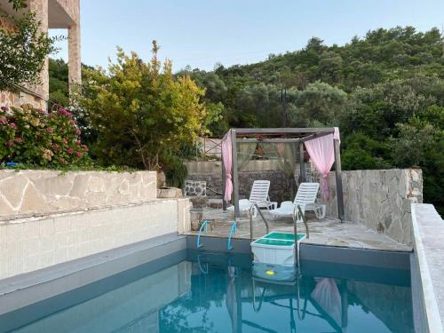 einen Pool mit zwei Stühlen und einem Pavillon in der Unterkunft Flower villa in Tivat