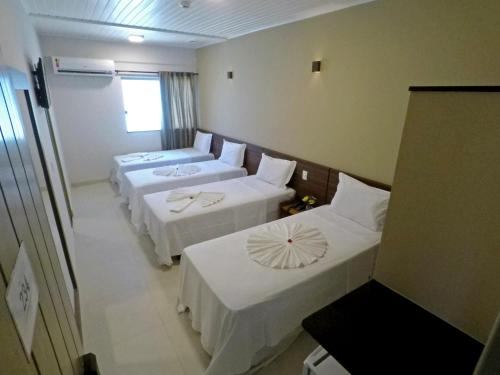 um quarto de hotel com três camas e uma janela em MIRAGE HOTEL em Porto Seguro