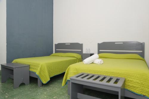 巴耶斯城的住宿－Hotel El Detalle，一间卧室配有两张带黄床单和长凳的床。