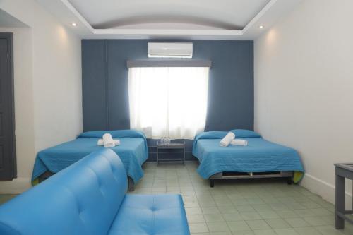 a blue room with two beds and a couch at Hotel El Detalle in Ciudad Valles