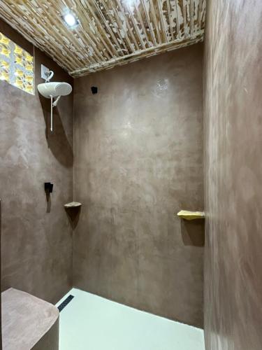 a bathroom with a concrete wall with a ceiling at Pousada Horizonte Azul in Ilha de Boipeba