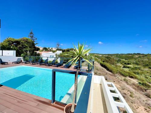 a swimming pool with a palm tree on a deck at Zambujeira Terrace in Zambujeira do Mar