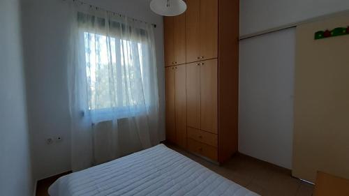 a bedroom with a white bed and a window at Nickolas Tiny apartment Souda-Chania in Chania Town